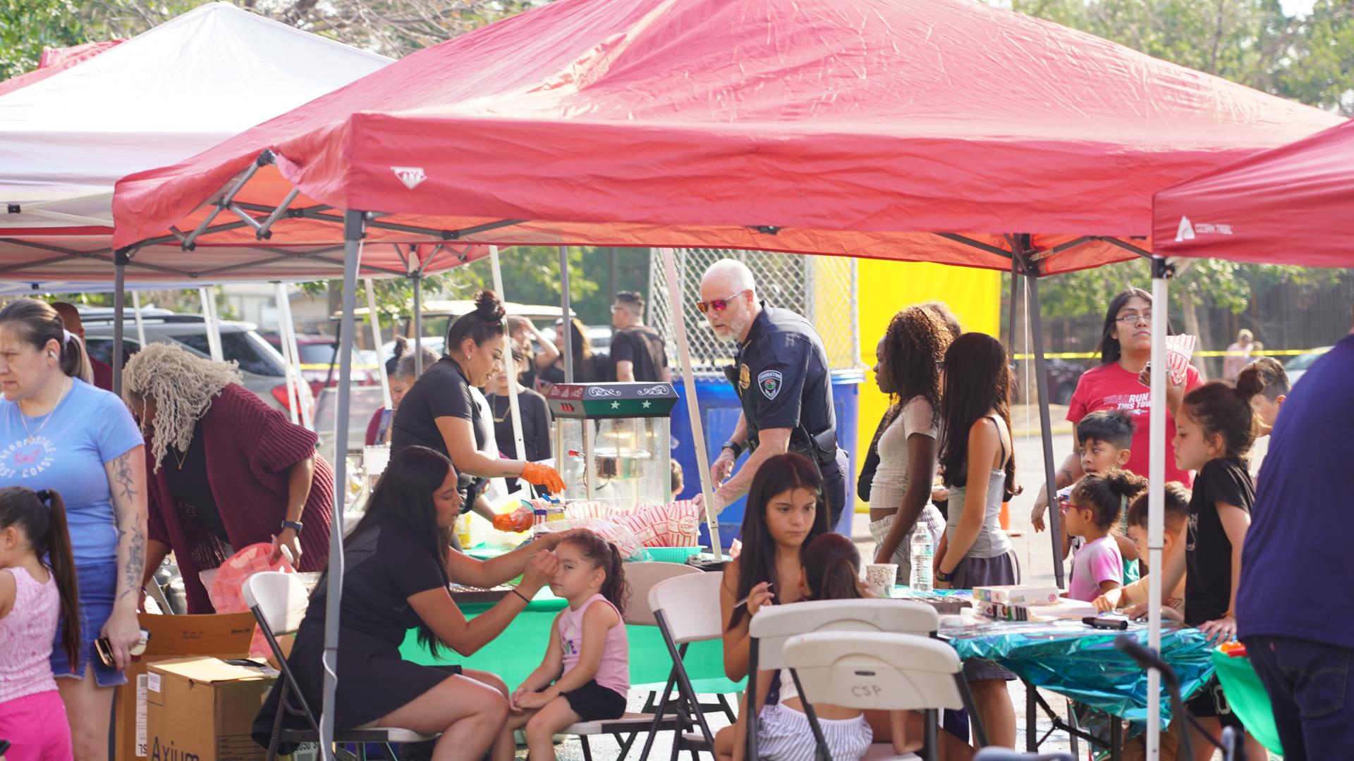 crowd with kids getting faces painted, families getting food