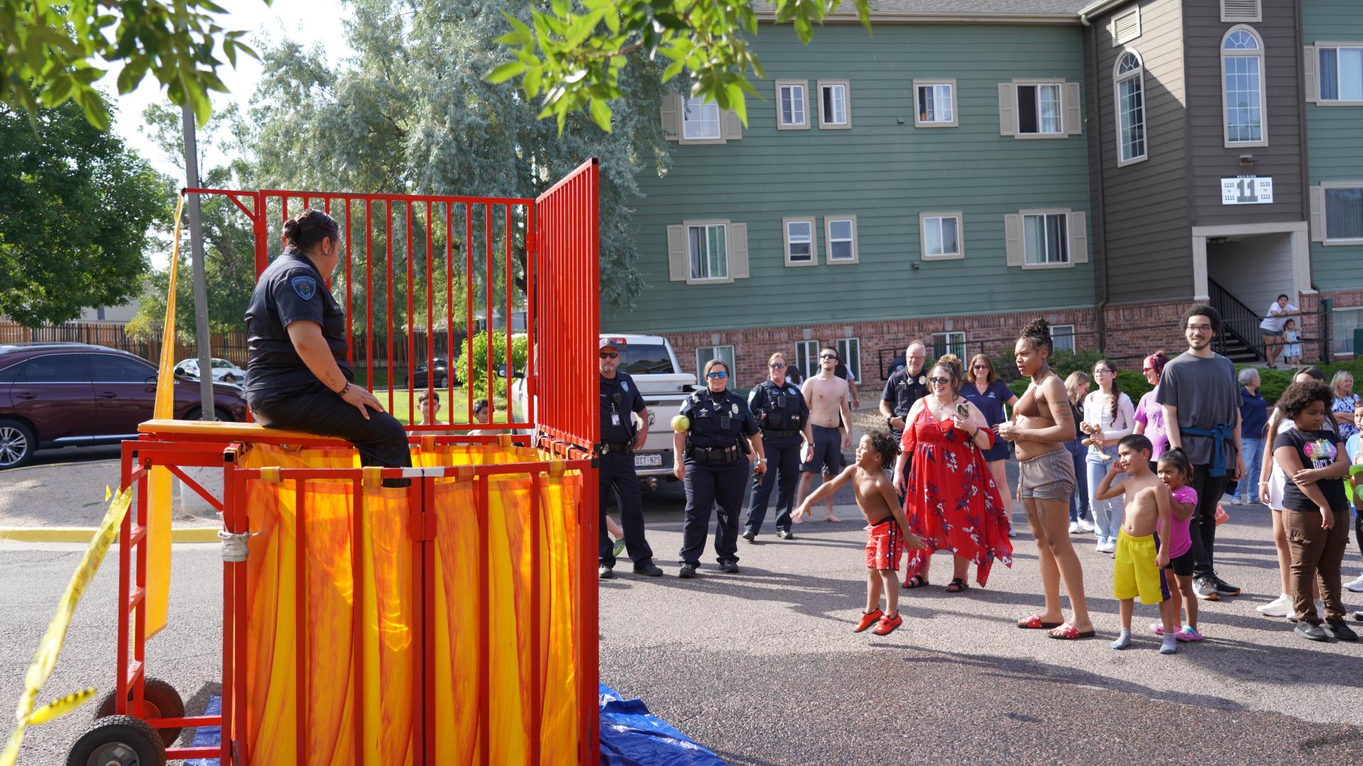 police officer sitting on dunk tank seat with crowd surrounding her to watch