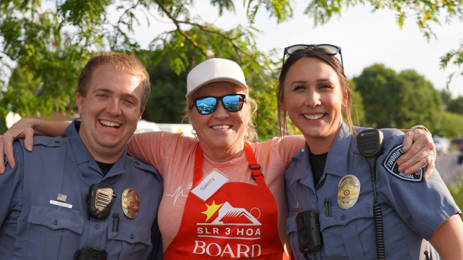 two animal control officers being hugged by woman in barbecue apron