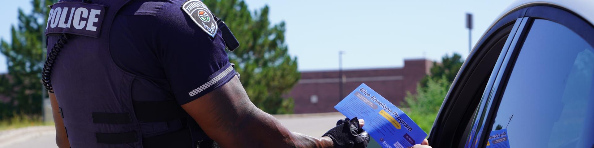 Driver handing a blue envelope to police officer
