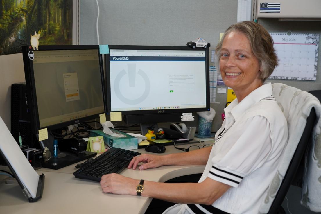 Records specialist smiling at the camera sitting at their desk